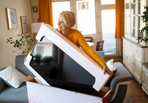 Woman unpacking new television from large box